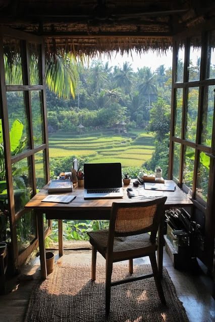 A laptop on a desk looking out over green hills