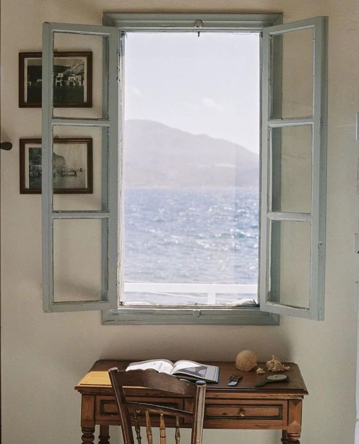 Open shutters onto the sea and mountains from a writing desk